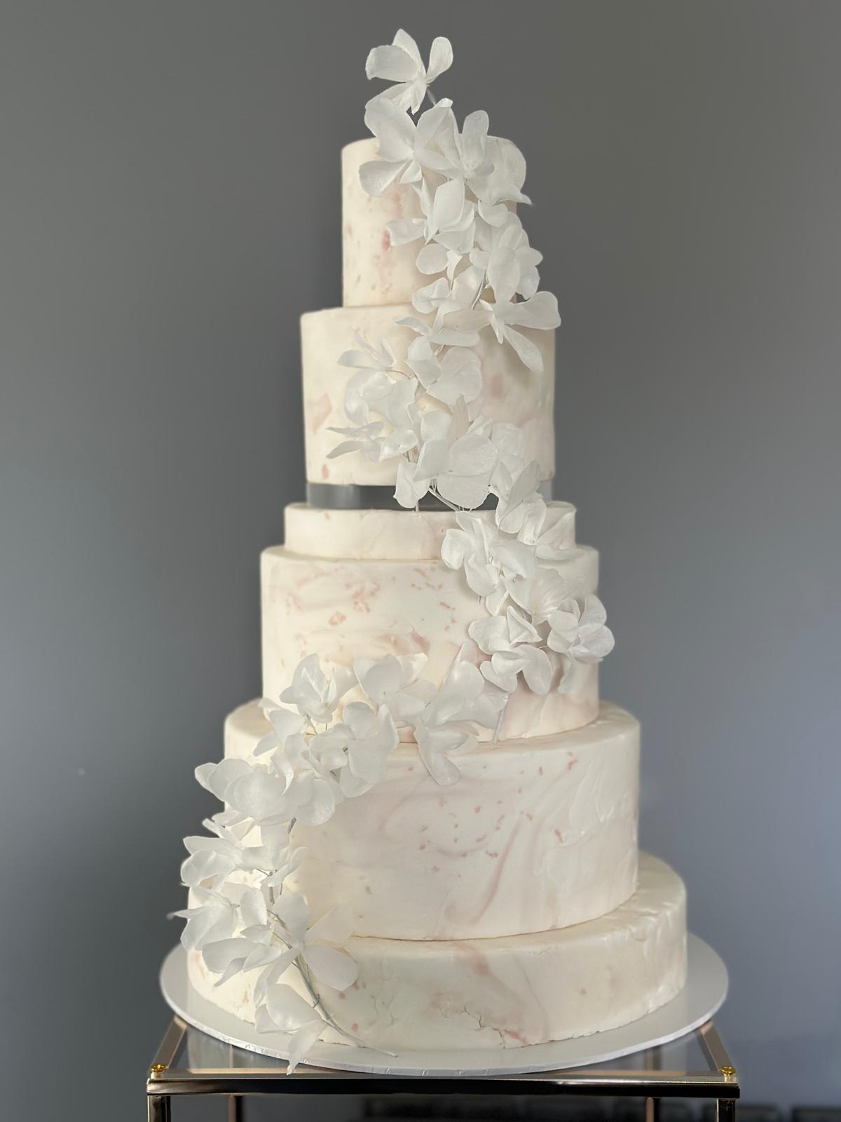 Five-tier blush marble wedding cake with cascading white wafer paper flowers, luxury wedding cakes London