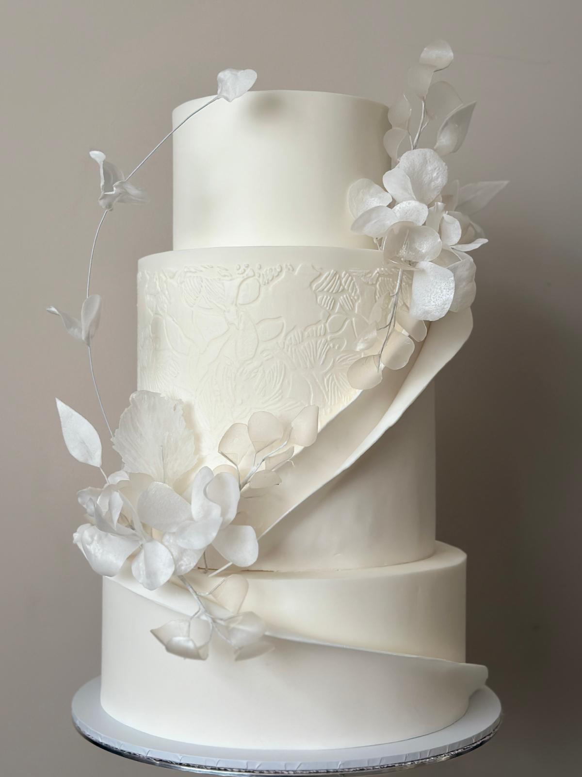 White sculptural wedding cake with wrap detail and wafer paper flowers West London